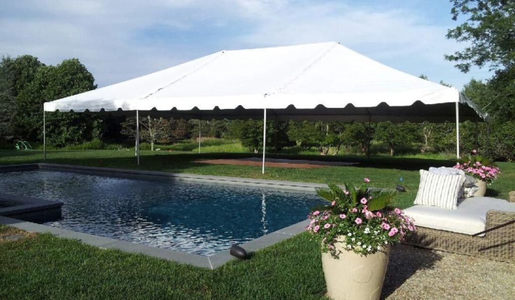 White frame tent rental set up in a backyard next to a pool on Long Island for a bridal shower