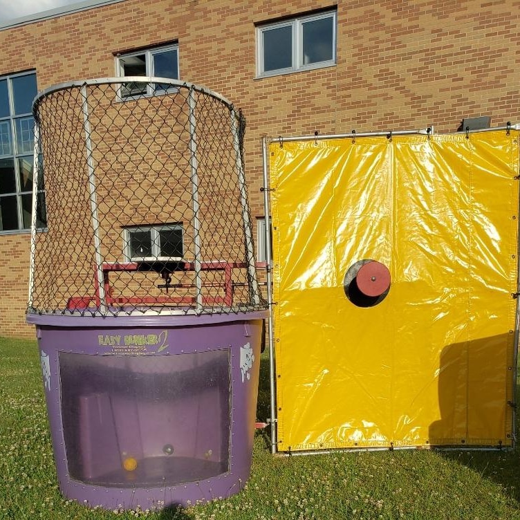 Dunk tank rental set up on grass outside a school or community building for a kids birthday party or outdoor event in Nassau County