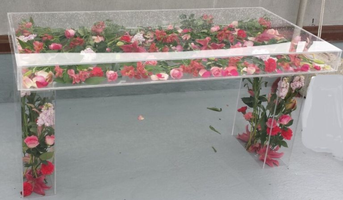Acrylic ghost table filled with pink and red fresh flowers used as a specialty rental display table for a Long Island event or party